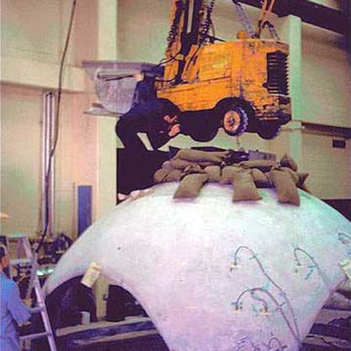 Testing the strength of concrete domes at BYU Laboratories. The sand bags represent the amount of weight previously thought to be the maximum load this dome could take. The addition of the forklift did nothing.