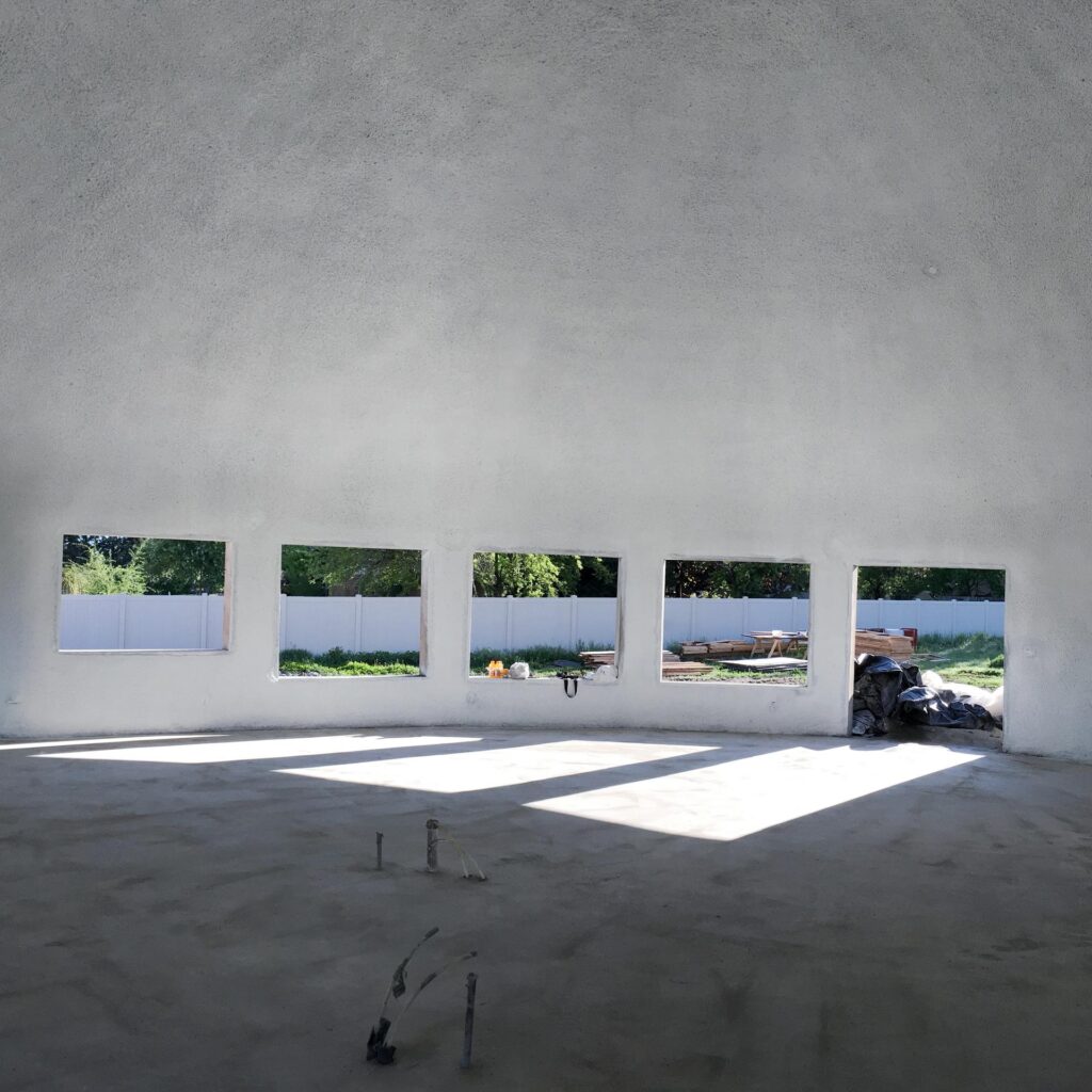 The Arcadia Home: The finished shotcrete layer completes the dome construction process. The stem walls are now open, revealing large windows that let plenty of natural light into the space.